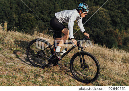 Equipped Professional Cyclist Descends a Slope on His Mountain Bike, Sportsman Going Down from Hill on Bicycle 92640361