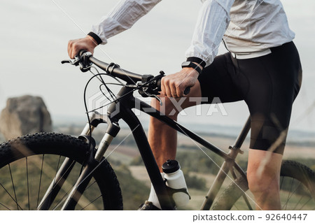 Cropped Unrecognizable Professional Male Cyclist Sitting on His Bike Outdoors, Sportsman Riding on Trail Track Cropped Unrecognizable Professional Male Cyclist Sitting on His Bike Outdoors, Sportsman Riding on Trail Track 92640447