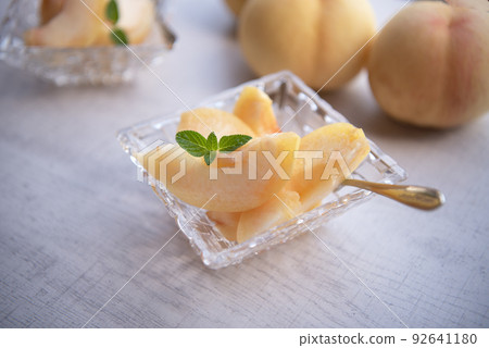 Pieces of japanese white peach in glass bowl on wooden background. 92641180