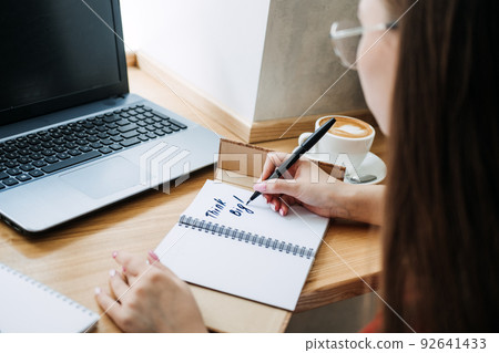 Worker or student woman writing Think big motivational phrase in open notebook 92641433