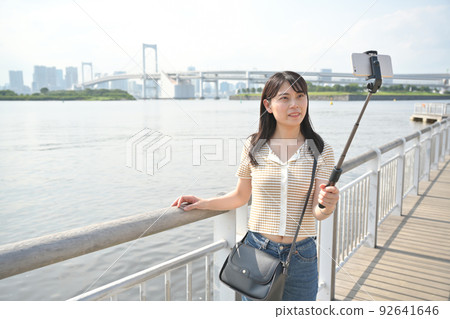一個女人用智能手機在海灘上用自拍杆拍照 一個女人用智能手機在海灘上用自拍杆拍照 92641646