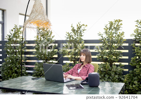 Woman works on laptop online in the garden outdoors 92641704
