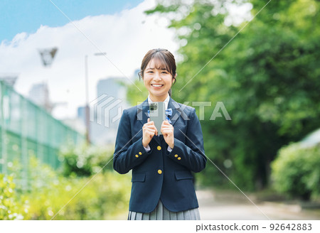 A high school girl with a smartphone in the park 92642883