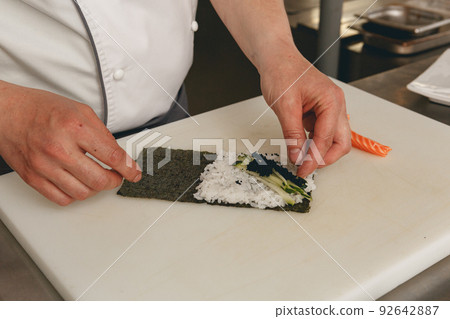 Chef hands cooking sushi with rice, salmon and nori on kitchen of japanese restaurant Chef hands cooking sushi with rice, salmon and nori on kitchen of japanese restaurant 92642887