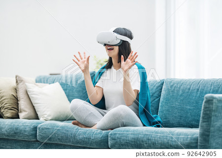 Woman enjoying VR in her living room 92642905