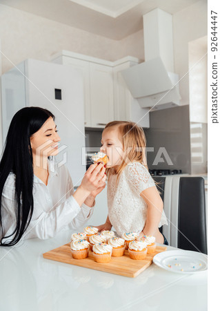 Mother gives daughter to eat delicious muffins with cream 92644447
