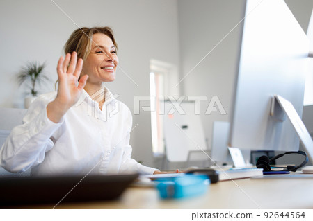 Smiling business woman waving hello talking on video call 92644564