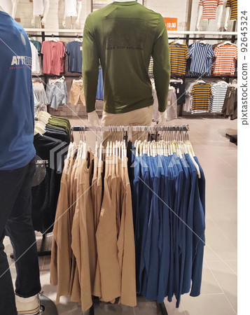 SELANGOR, MALAYSIA -APRIL 4, 2022: Various types of clothes are being sold in the store. Displayed by hanging and folding. Have a price tag for buyer review. Separated by type and brand 92645324