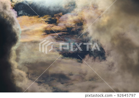 Diffraction of light on drops of supercooled water in clouds, rainbow clouds against the blue sky in clear sunny weather, irisation of cumulus clouds, optical phenomenon, spectral colors Diffraction of light on drops of supercooled water in clouds, rainbow clouds against the blue sky in clear sunny weather, irisation of cumulus clouds, optical phenomenon, spectral colors 92645797