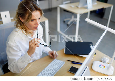 Thoughtful mature business woman is working on a computer at the workplace in office 92646399