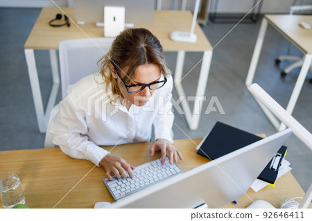 Middle aged business woman is concentrated on working at a computer Middle aged business woman is concentrated on working at a computer 92646411