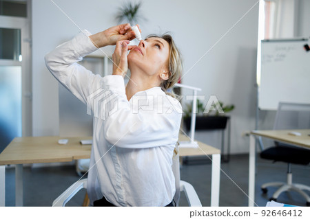 Beautiful woman office worker feels eye fatigue and applies eye drops. Beautiful woman office worker feels eye fatigue and applies eye drops. 92646412