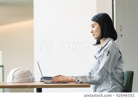 一個穿著工作服在電腦上工作的女人 一個穿著工作服在電腦上工作的女人 92646581