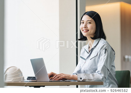A woman in work clothes working on a computer A woman in work clothes working on a computer 92646582