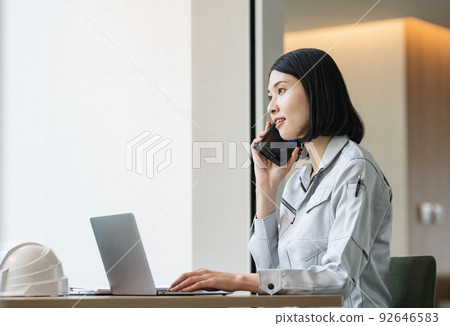 A woman in work clothes talking on a smartphone A woman in work clothes talking on a smartphone 92646583