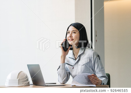一個穿著工作服的女人用智能手機說話 92646585