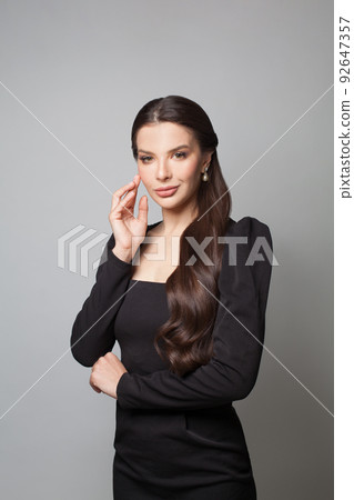 Perfect woman fashion model with dark long hair wearing black dress posing on white background Perfect woman fashion model with dark long hair wearing black dress posing on white background 92647357