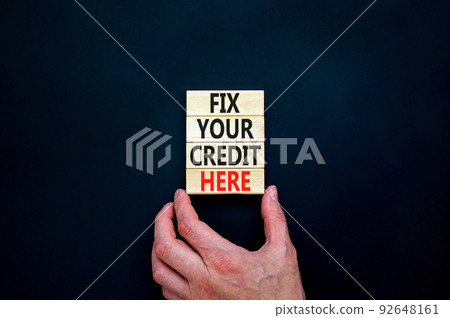 Fix your credit here symbol. Concept words Fix your credit here on wooden blocks on a beautiful black table black background. Businessman hand. Business, finacial and fix your credit here concept. 92648161