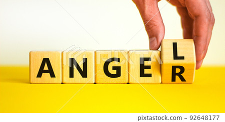 Having anger or being an angel. Businessman turns a wooden cube and changes the word anger to angel. Beautiful white background. Business and anger or angel concept. Copy space. 92648177