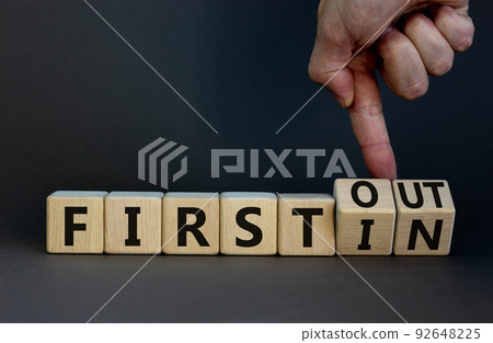 First in first out symbol. Businessman turns wooden cubes and changes words first in to first out. Beautiful grey table, grey background. Business and first in and out concept. Copy space. First in first out symbol. Businessman turns wooden cubes and changes words first in to first out. Beautiful grey table, grey background. Business and first in and out concept. Copy space. 92648225