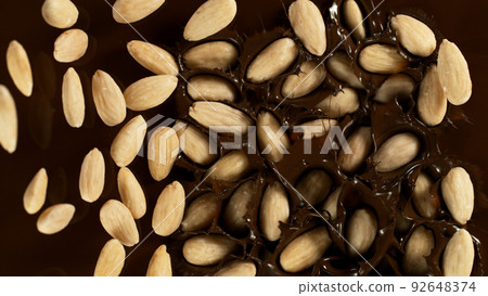 Falling Blanched Almonds into Dark Hot Melted Chocolate, Close-up, Top Shot. Falling Blanched Almonds into Dark Hot Melted Chocolate, Close-up, Top Shot. 92648374