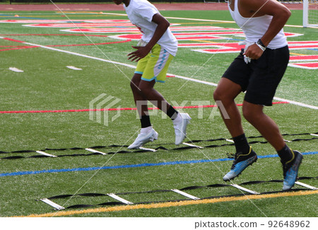 Football players running a ladder agility drill at summer camp 92648962