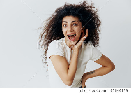 HUGE SALE OFFER. Enjoyed excited pensive Latin female with waving afro hair, hold hand near face, say Wow, looking at camera, stay isolated on white background. Copy space, free place, fashion banner HUGE SALE OFFER. Enjoyed excited pensive Latin female with waving afro hair, hold hand near face, say Wow, looking at camera, stay isolated on white background. Copy space, free place, fashion banner 92649199