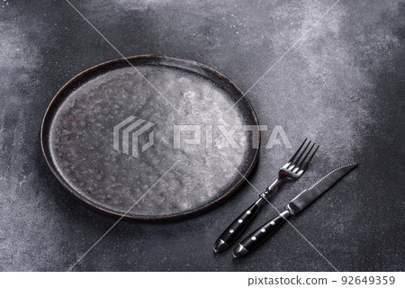 Black plate on a black background. Flat lay, top view, copy space Black plate on a black background. Flat lay, top view, copy space 92649359