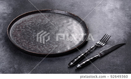 Black plate on a black background. Flat lay, top view, copy space 92649360