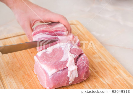 man cuts meat with knife on wooden board man cuts meat with knife on wooden board 92649518