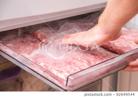 man puts minced pork and beef in the freezer in man puts minced pork and beef in the freezer in 92649544