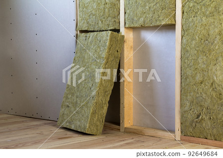 Wooden frame for future walls with drywall plates insulated with rock wool and fiberglass insulation staff for cold barrier. Comfortable warm home, economy, construction and renovation concept. Wooden frame for future walls with drywall plates insulated with rock wool and fiberglass insulation staff for cold barrier. Comfortable warm home, economy, construction and renovation concept. 92649684