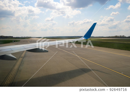 View of jet airplane wing taxiing runway after landing at airport. Travel and air transportation concept. View of jet airplane wing taxiing runway after landing at airport. Travel and air transportation concept. 92649716
