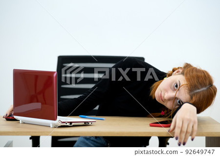 Tired office worker woman having a nap behind working desk. Tired office worker woman having a nap behind working desk. 92649747