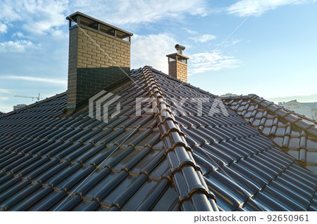 Closeup of house roof top covered with ceramic shingles. Tiled covering of building Closeup of house roof top covered with ceramic shingles. Tiled covering of building 92650961