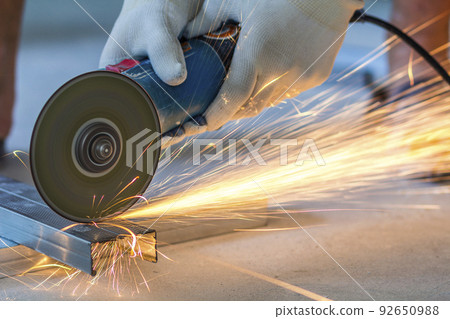 Close-up of worker cutting metal with grinder. Sparks while grinding iron. 92650988