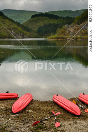 Inflatable red kayak boats laying on lake beach Inflatable red kayak boats laying on lake beach 92651842