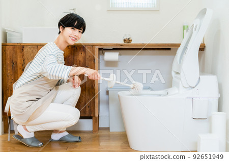 young woman cleaning the toilet young woman cleaning the toilet 92651949