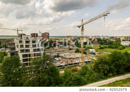 Aerial view of tower lifting crane and concrete frame of tall apartment residential building under construction in a city. Urban development and real estate growth concept. 92652079