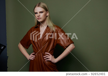 Women's Day concept. Stylish fashion self-confident young blonde woman holding hands on waist posing isolated on over olive green wall background looks at camera. Fashion offer for brands banner Women's Day concept. Stylish fashion self-confident young blonde woman holding hands on waist posing isolated on over olive green wall background looks at camera. Fashion offer for brands banner 92652401