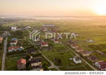 Aerial landscape of small town or village with rows of residential homes and green trees. Aerial landscape of small town or village with rows of residential homes and green trees. 92652624