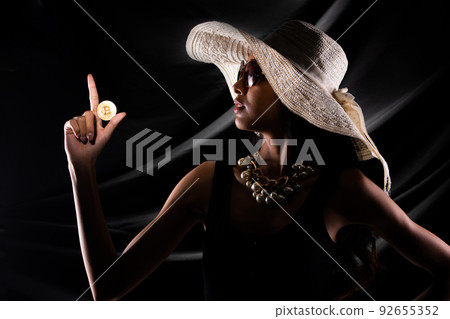 Silhouette of young woman hold gold bitcoin cryptocurrency trade online over drape curtain black 92655352