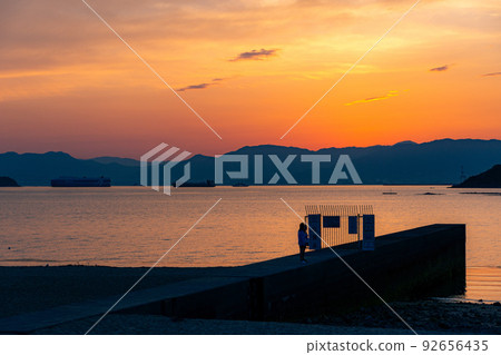 The sky and sea dyed in the sunset, and the people playing there The sky and sea dyed in the sunset, and the people playing there 92656435