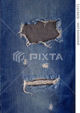 Blue jeans denim background texture. Torn jeans fabric material surface Blue jeans denim background texture. Torn jeans fabric material surface 92663571