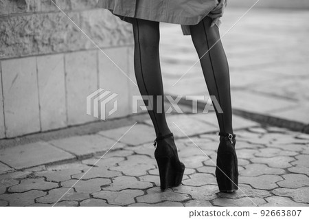 Sexy female legs in stockings and a raincoat. Black and white photo Sexy female legs in stockings and a raincoat. Black and white photo 92663807