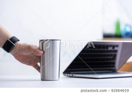 Male hand holding a stainless steel tumbler 92664659