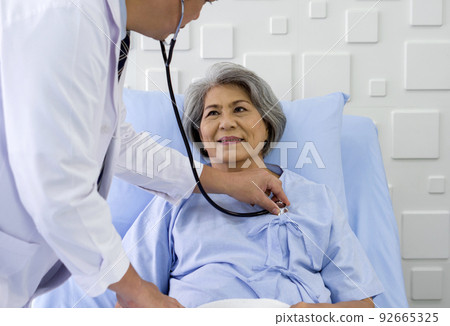 Senior female patient and doctor. Asian doctor use a stethoscope to check the heartbeat of the elderly patient. Senior female patient and doctor. Asian doctor use a stethoscope to check the heartbeat of the elderly patient. 92665325