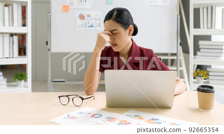 Young asian businesswoman massages between eyes with fingers. The concept of unemployed, sadness, depressed and human problems. 92665354