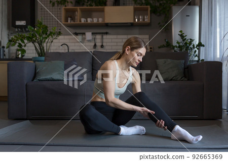 A woman injured her leg and knee at home during morning exercises, massages, and is in severe pain A woman injured her leg and knee at home during morning exercises, massages, and is in severe pain 92665369
