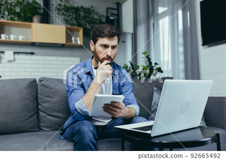 Male freelancer teaches remotely, uses laptop, looks at webcam, explains economic theory to students Male freelancer teaches remotely, uses laptop, looks at webcam, explains economic theory to students 92665492
